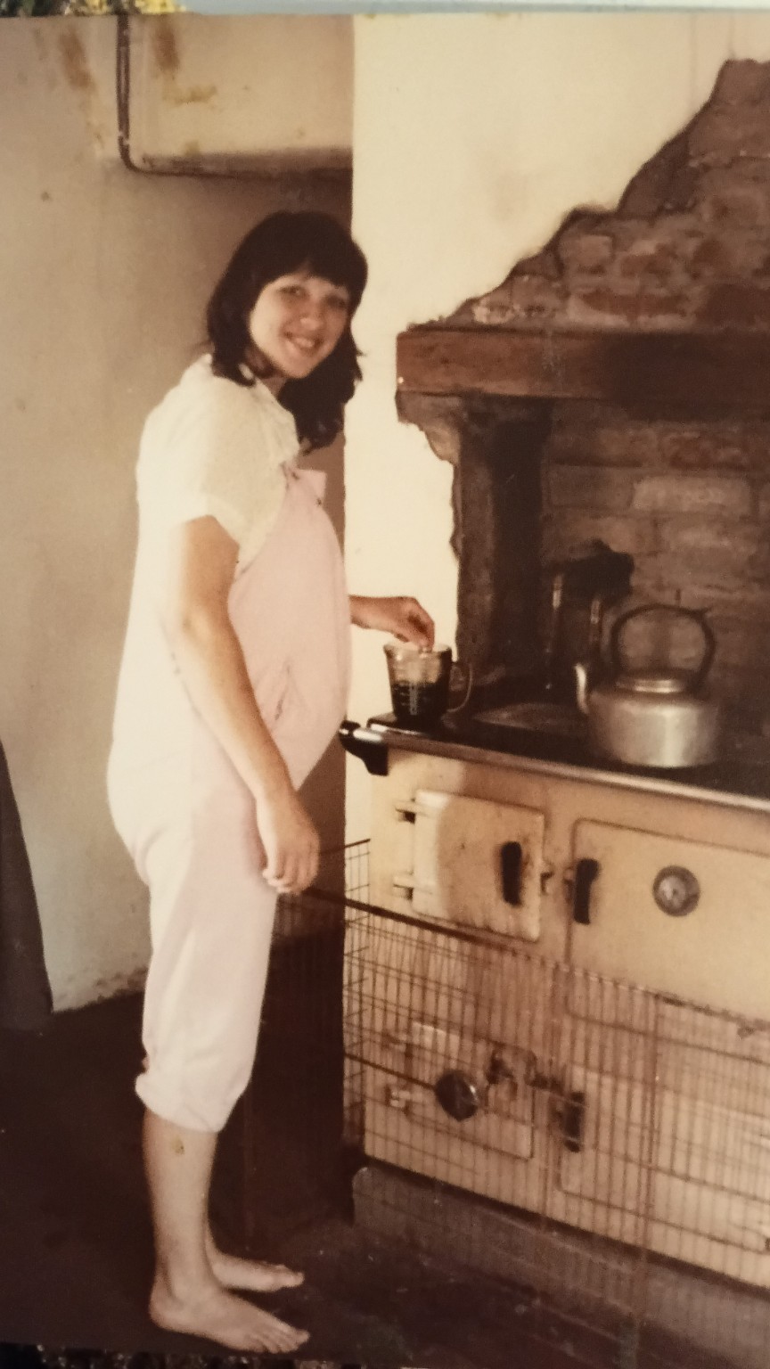 Family photograph of Branwen, pregnant, standing at the kitchen range inside Great House Farm.